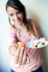 Cute young woman eating jelly candies with a fresh smile