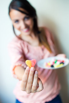 Cute young woman eating jelly candies with a fresh smile