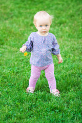 Funny cute baby girl with flower on a meadow