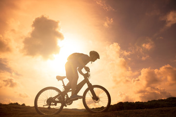 Fototapeta na wymiar The silhouette of mountain bicycle rider on the hill