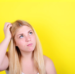 Fototapeta premium Portrait of beautiful girl thinking and looking up against yello