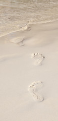 Footprints on  the beach walk to ocean seashore