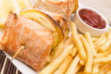 Salmon skewers with fries closeup