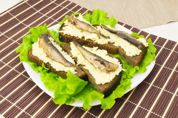 Sprats on bread with cheese and garlic