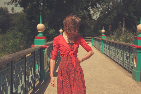 Woman wearing a red dress on bridge in a park