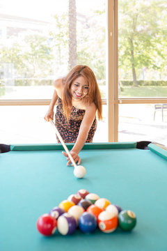 Smiling woman playing pool.