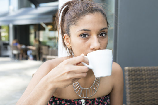 Closeup portrait of beautiful latin woman drinking coffee.