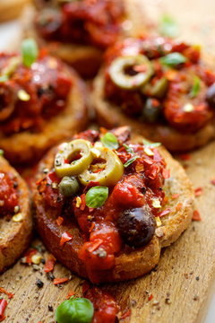 Crostini with roasted tomto sauce, olives, capers and herbs