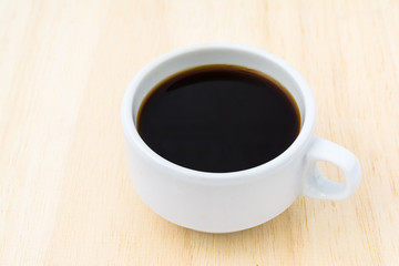 Black coffee in a white cup on wood.