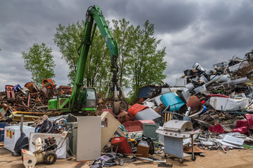 a green hydraulic equipement working in a scrap yard