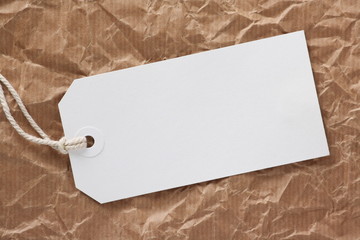 Blank white luggage tag on crumpled parcel paper
