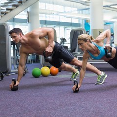 Fototapeta na wymiar Bodybuilding man and woman lifting kettlebells in plank position