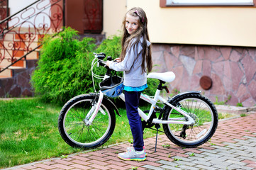 Adorable kid girl in blue helmet riding her bike  