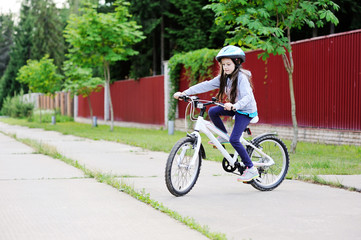 Adorable kid girl in blue helmet riding her bike  
