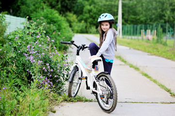 Adorable kid girl in blue helmet riding her bike  