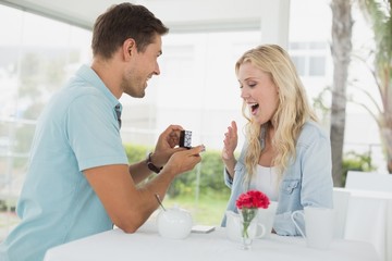 Obraz na płótnie Canvas Man proposing marriage to his shocked blonde girlfriend