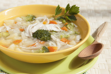 Broccoli soup with chicken, carrots, potatoes and parsley in yel