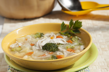 Broccoli soup with chicken, carrots, potatoes and parsley in yel