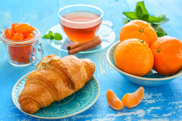 cup of tea, croissant and mandarines