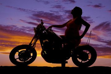 Fototapeta na wymiar silhouette pregnant woman on motorcycle side hand on tank