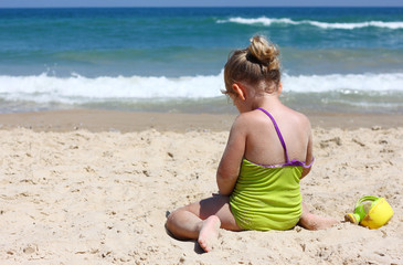 Fototapeta na wymiar cute kid laying on sand beach at the sea