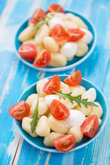 Boiled gnocchi with sliced mozzarella, red tomatoes and arugula