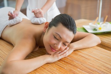 Obraz na płótnie Canvas Smiling brunette getting a herbal compress massage