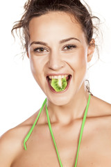 beautiful girl holding a piece of kiwi in the mouth