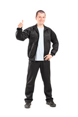 Fototapeta premium Young man in black tracksuit giving a thumb up