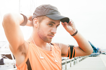Young handsome runner leaning against railing early morning