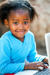 Cute african girl typing on laptop.