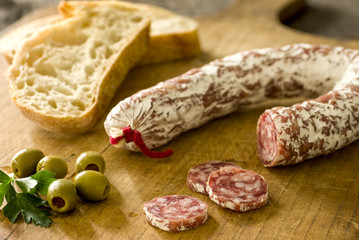 Ringsalami mit Baguette und grünen Oliven