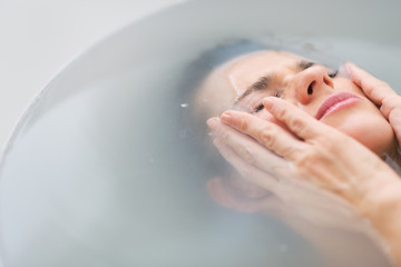 Stressed young woman laying in bathtub