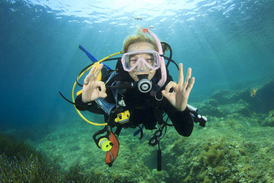 Young woman scuba diving signals okay