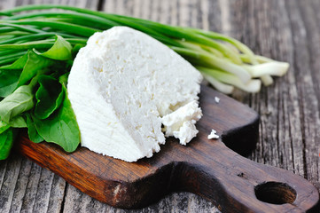 Cheese with arugula and onion on a wooden board