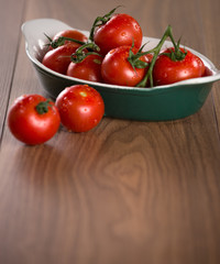 Ripe cherry tomatoes in a bowl on a wooden table