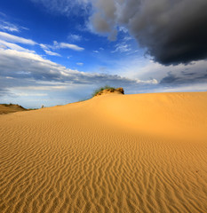 dunes in sandy desert under thunder sky