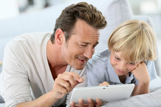 Man with little boy playing with digital tablet