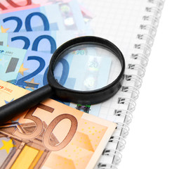 Magnifier and money on a notebook.