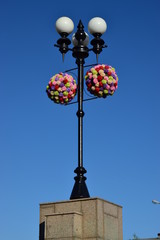 Fototapeta na wymiar A street lantern decorated with artificial flowers
