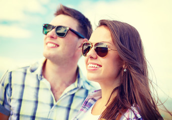 smiling teenagers in sunglasses having fun outside