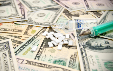 Tablets, a syringe on dollars.