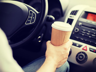 man drinking coffee while driving the car