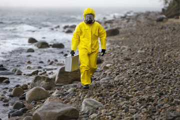 specialist in protective suit walking on rocky beach