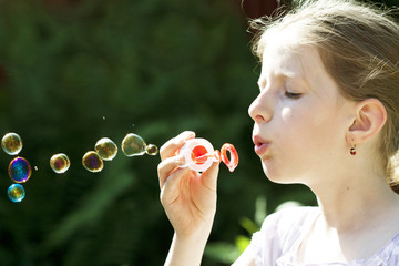 Young girl blowing soap bubbles