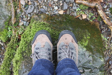 Feet in jeans and hiking shoes, on a stone