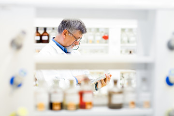 Senior doctor/scientist using his tablet computer at work (color