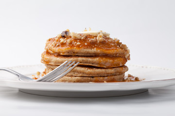 Wholesome homemade whole wheat pancakes on a white background topped with walnuts and apricot sauce