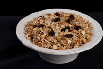 Bowl of homemade granola with oats, almonds, organic raisins, and walnuts