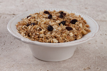 Isolated bowl of homemade granola with oats, almonds, organic raisins, and walnuts